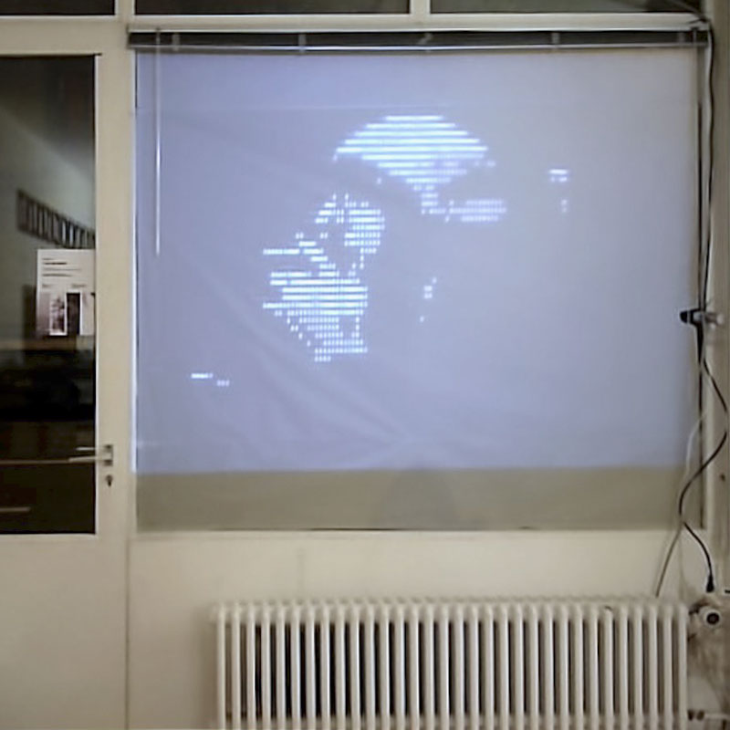 Photo of a man's image projected on the front window of Labo after being processed into ASCII