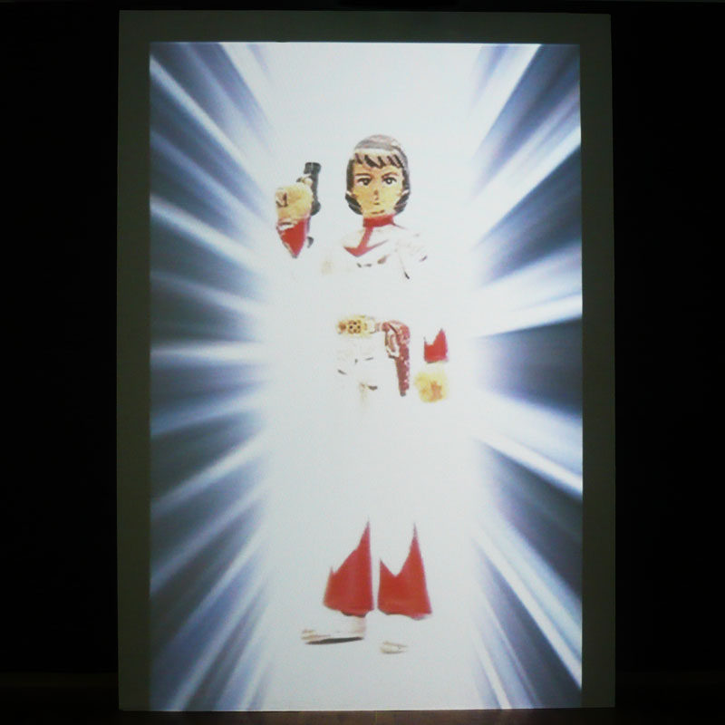 Photo of the video of a figurine of a man projected on a piece of wood